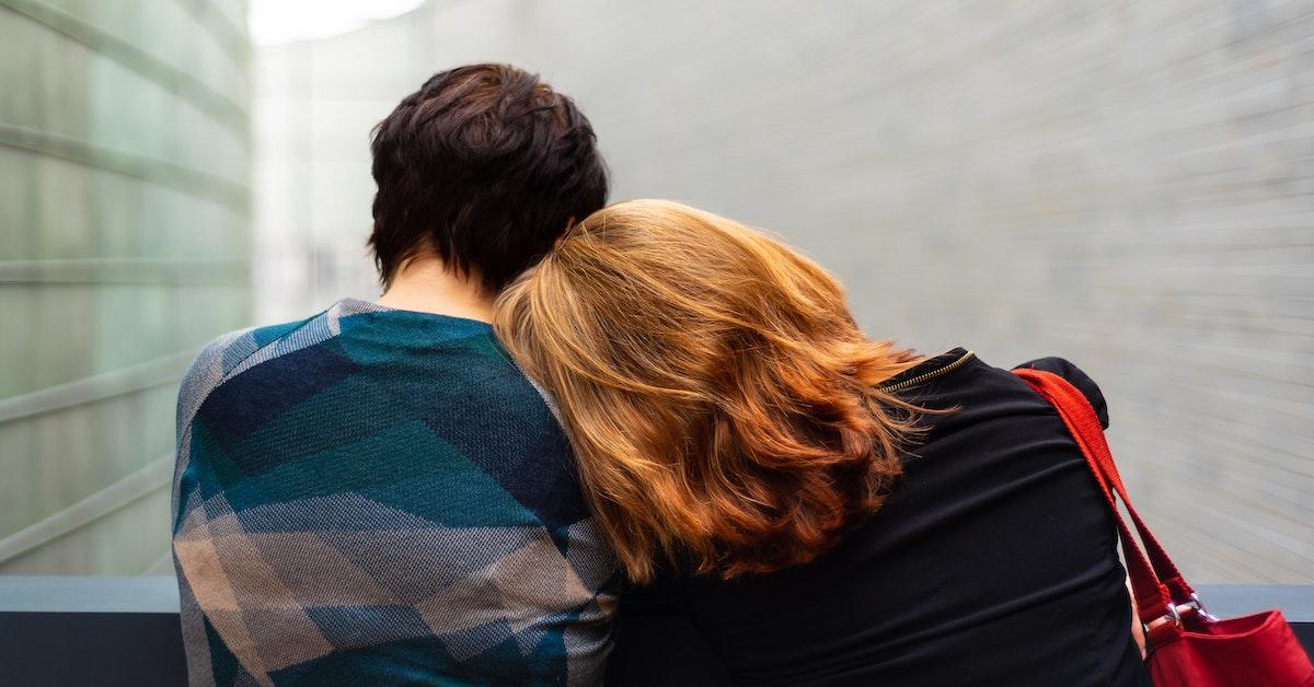 One person leaning on another's shoulder with their back to the camera.