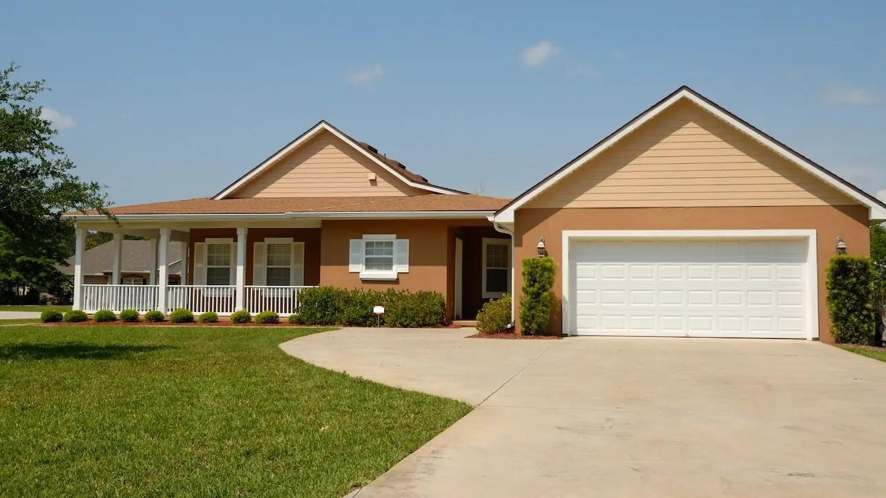 A tan colored house with a large driveway