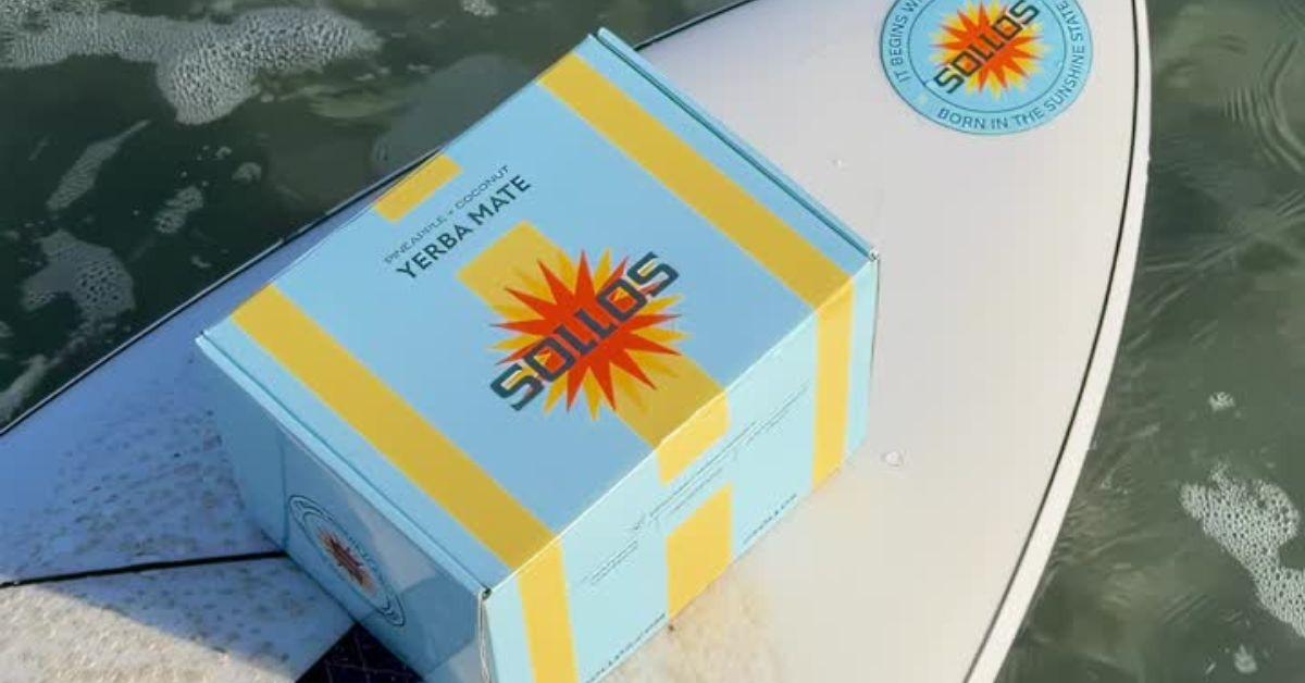 A box of Sollos beverages on a surfboard. 