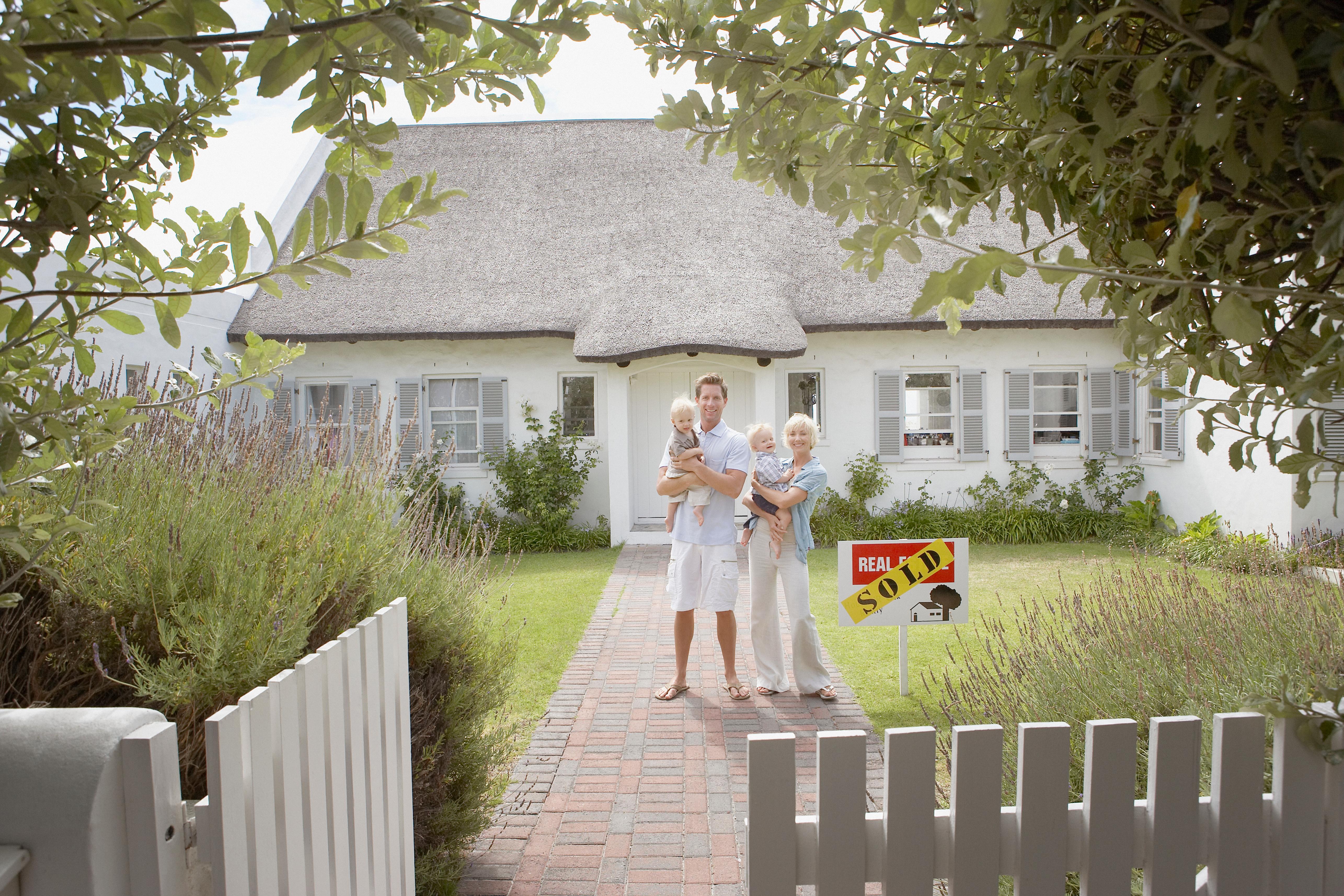 family posing in front of recent sold home.