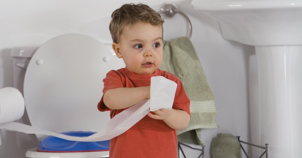 A toddler playing with toilet paper