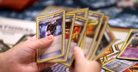 A child holds a collection of newer Pokémon cards.