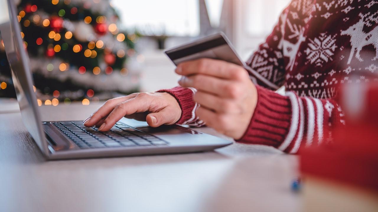 A person in a holiday sweater buying something online. 