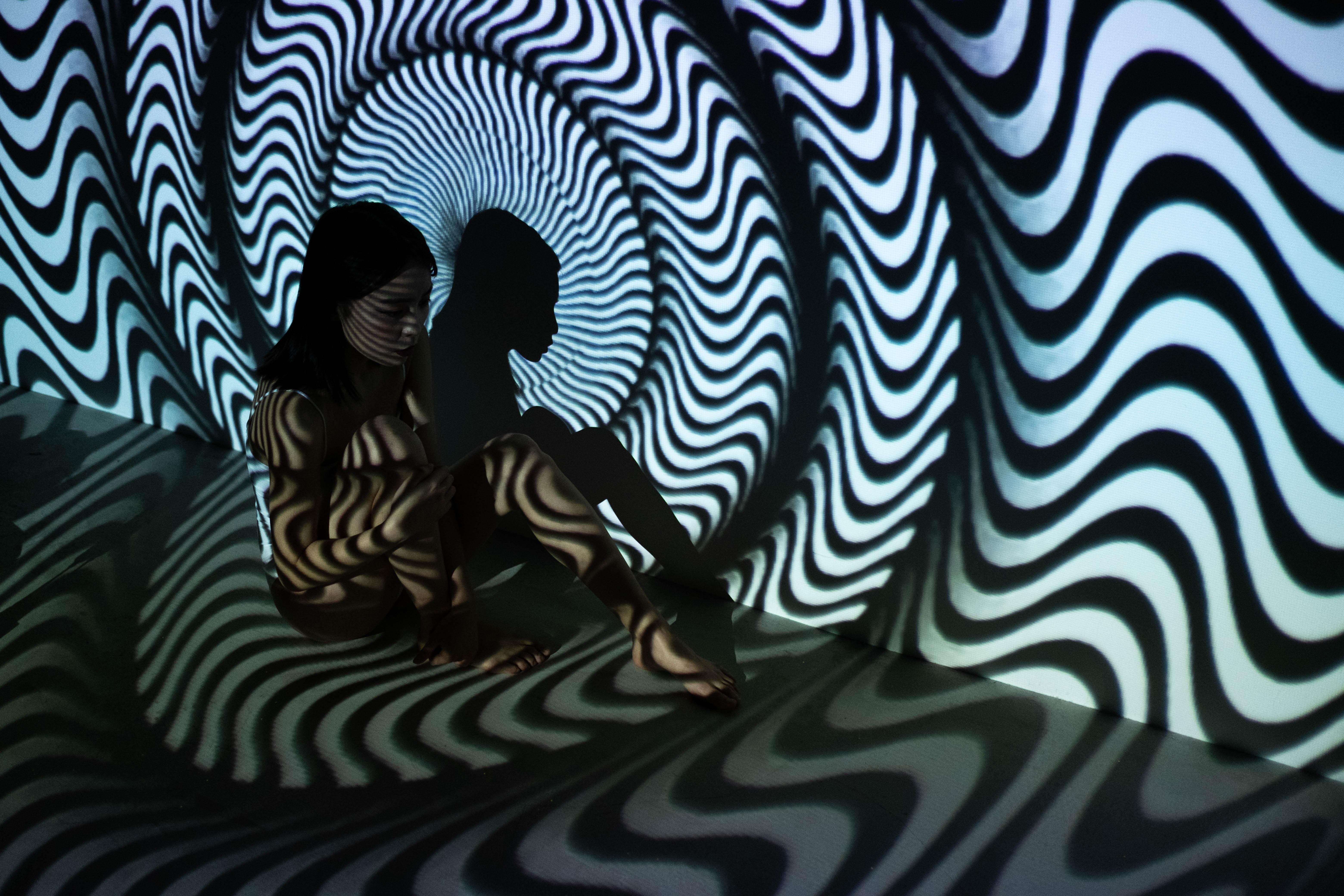 A person sitting in front of psychedelic art