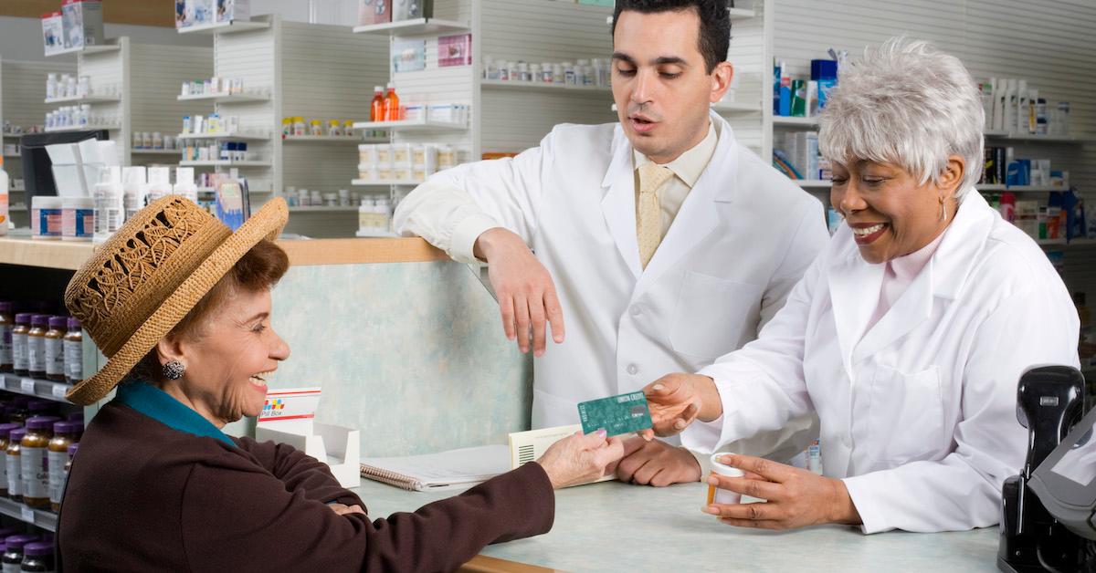 older woman paying pharmacist with debit card