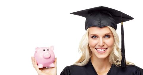 A woman in a cap and gown holding a piggy bank