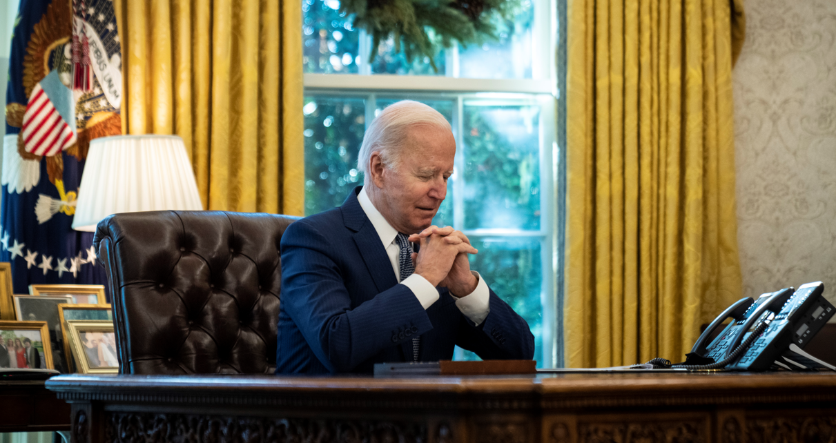 President Biden sitting at desk with hands clasped