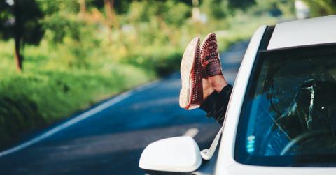A personal relazing with their feet out of a car