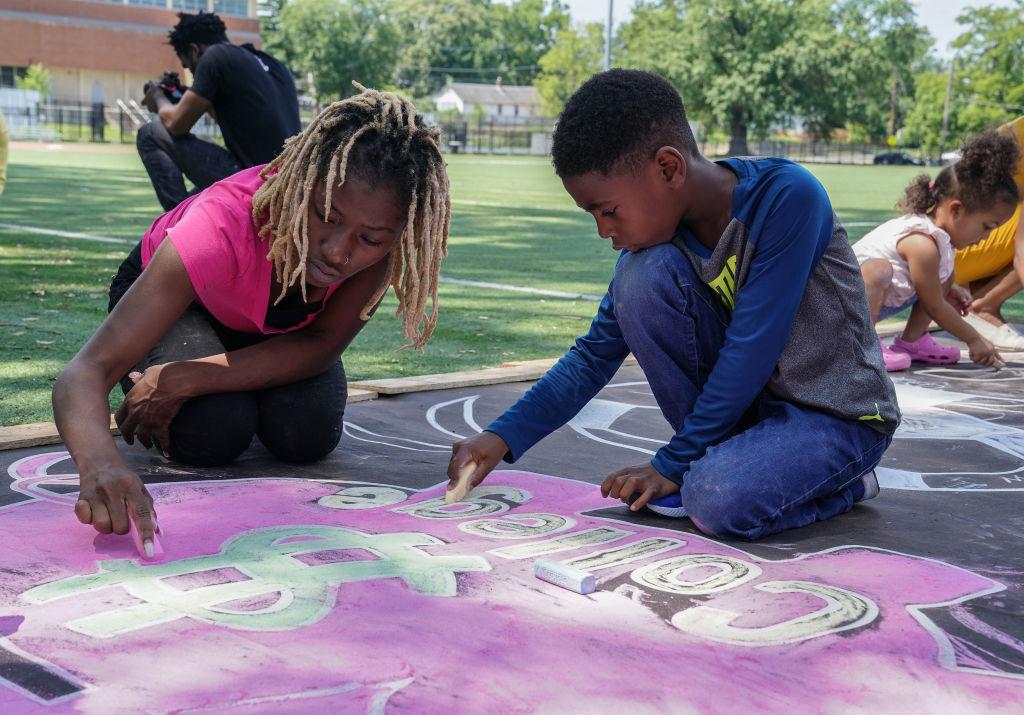 Parents and children drawing with chalk on pavement