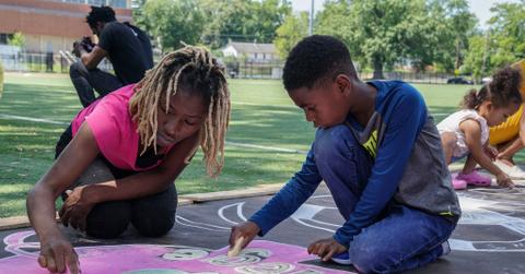 Parents and children drawing with chalk on pavement