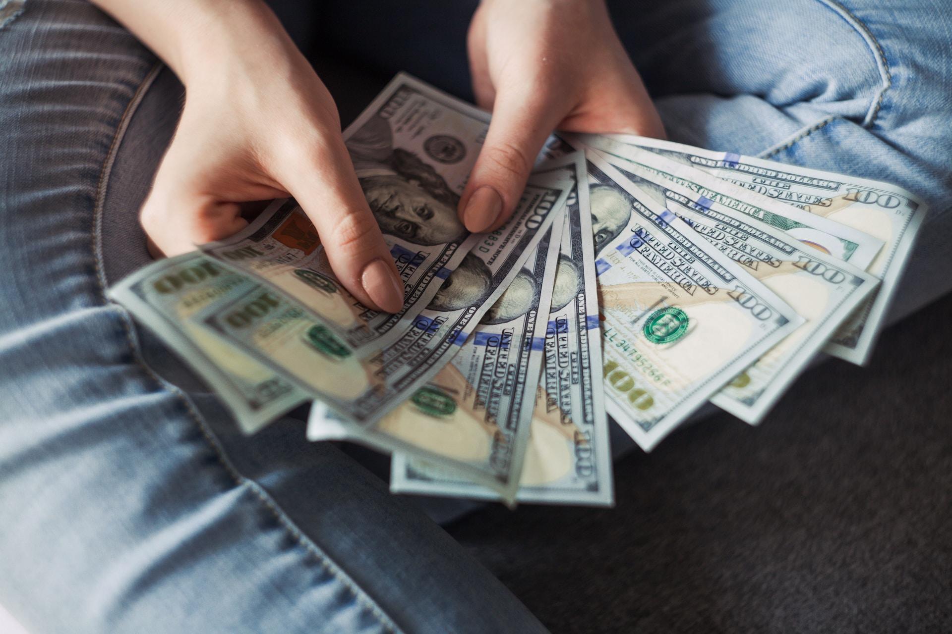 A person holding 100 dollar bills fanned out on display