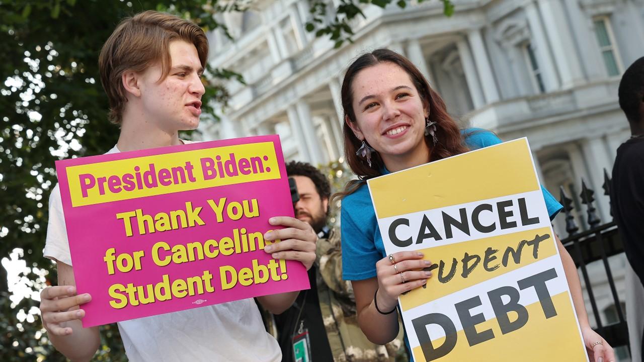 Students holding signs about loan forgiveness