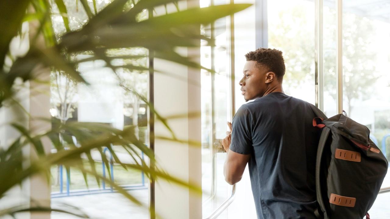 college student wearing backpack exiting door