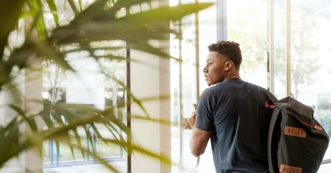 college student wearing backpack exiting door