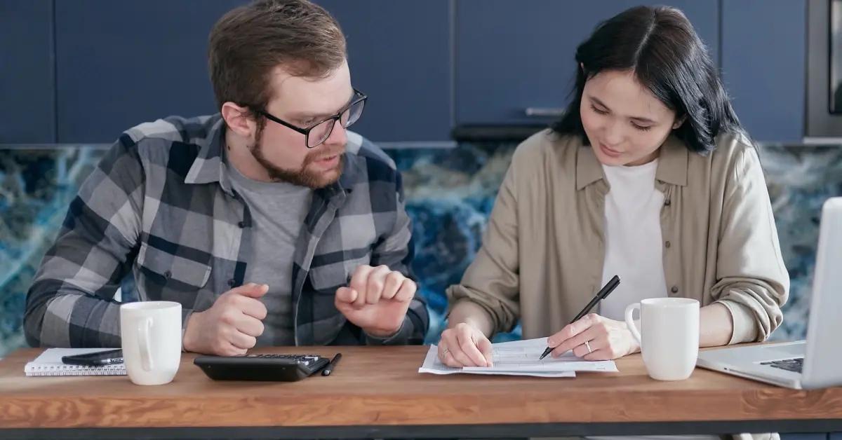 A couple sitting at a table filling out their tax forms together.