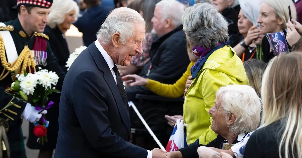 King Charles in suit and tie outside greeting community members.