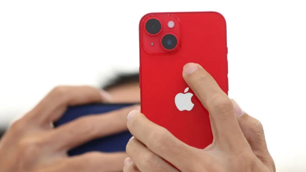 A woman holding a red iPhone 14