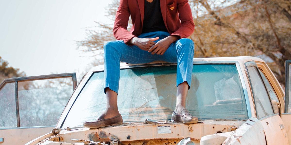 A person sitting on top of a damaged car