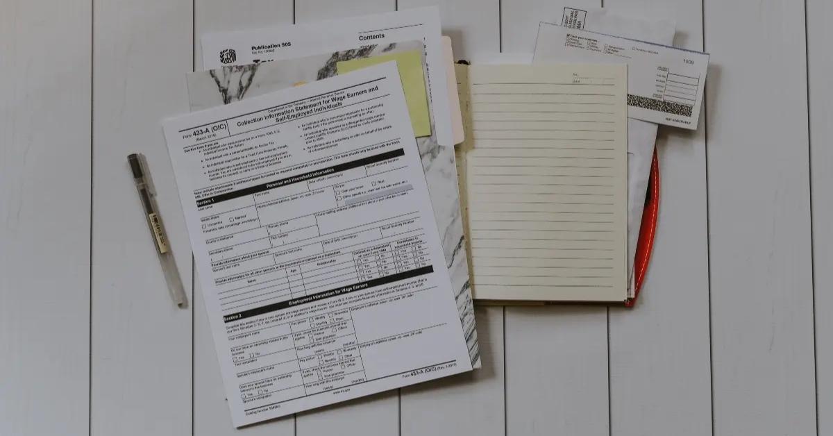 A small pile of tax documents sit on a desk.