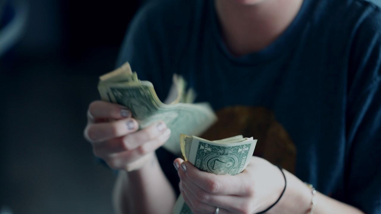 A person counting dollar bills