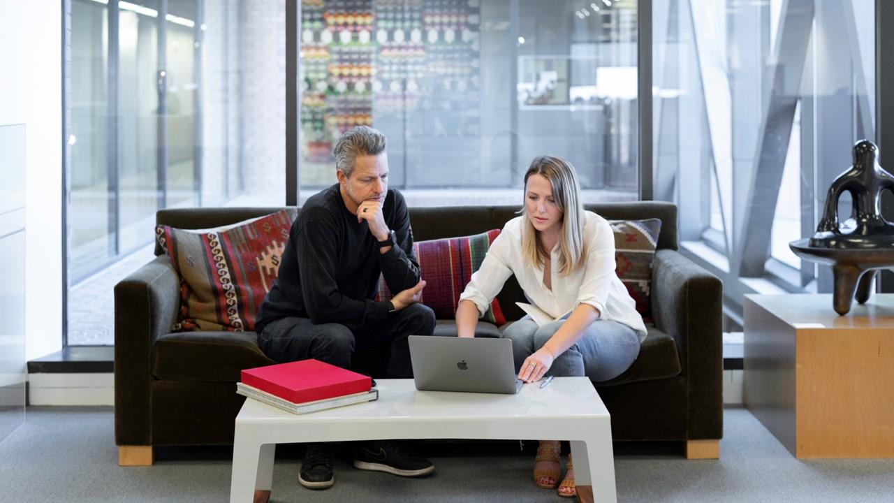 people in office looking at computer sitting on couch