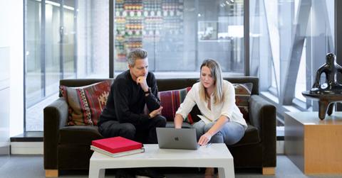 people in office looking at computer sitting on couch