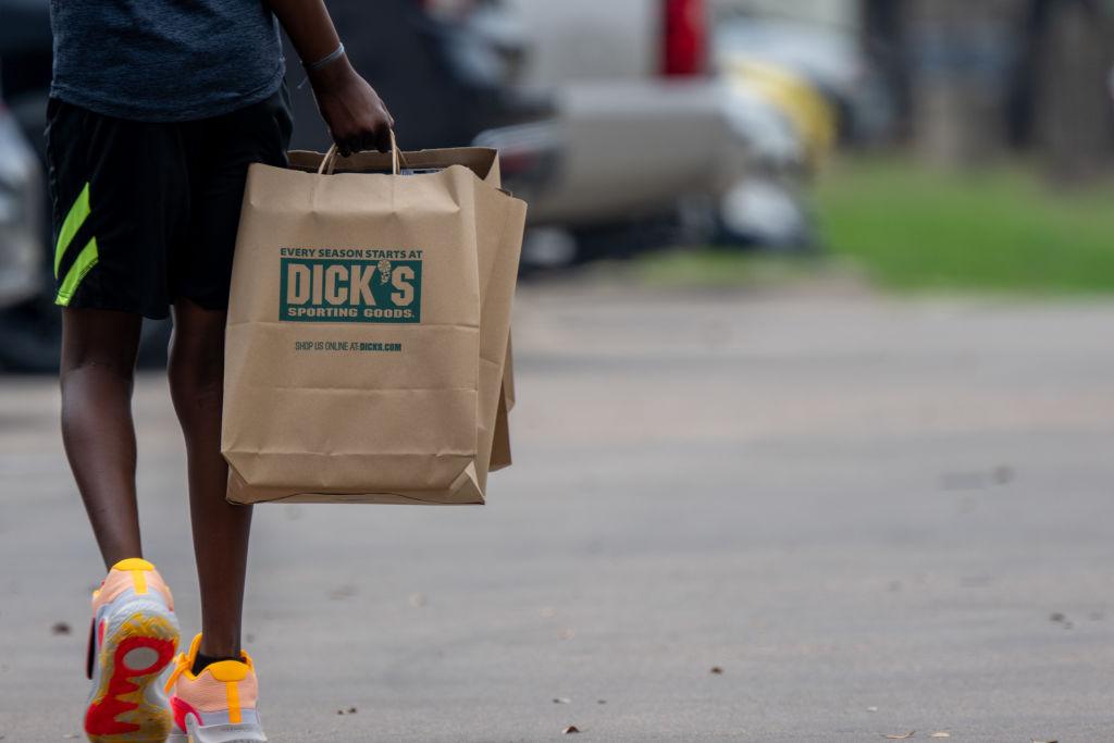 A man carrying a Dick's Sporting Goods bag in a parking lot