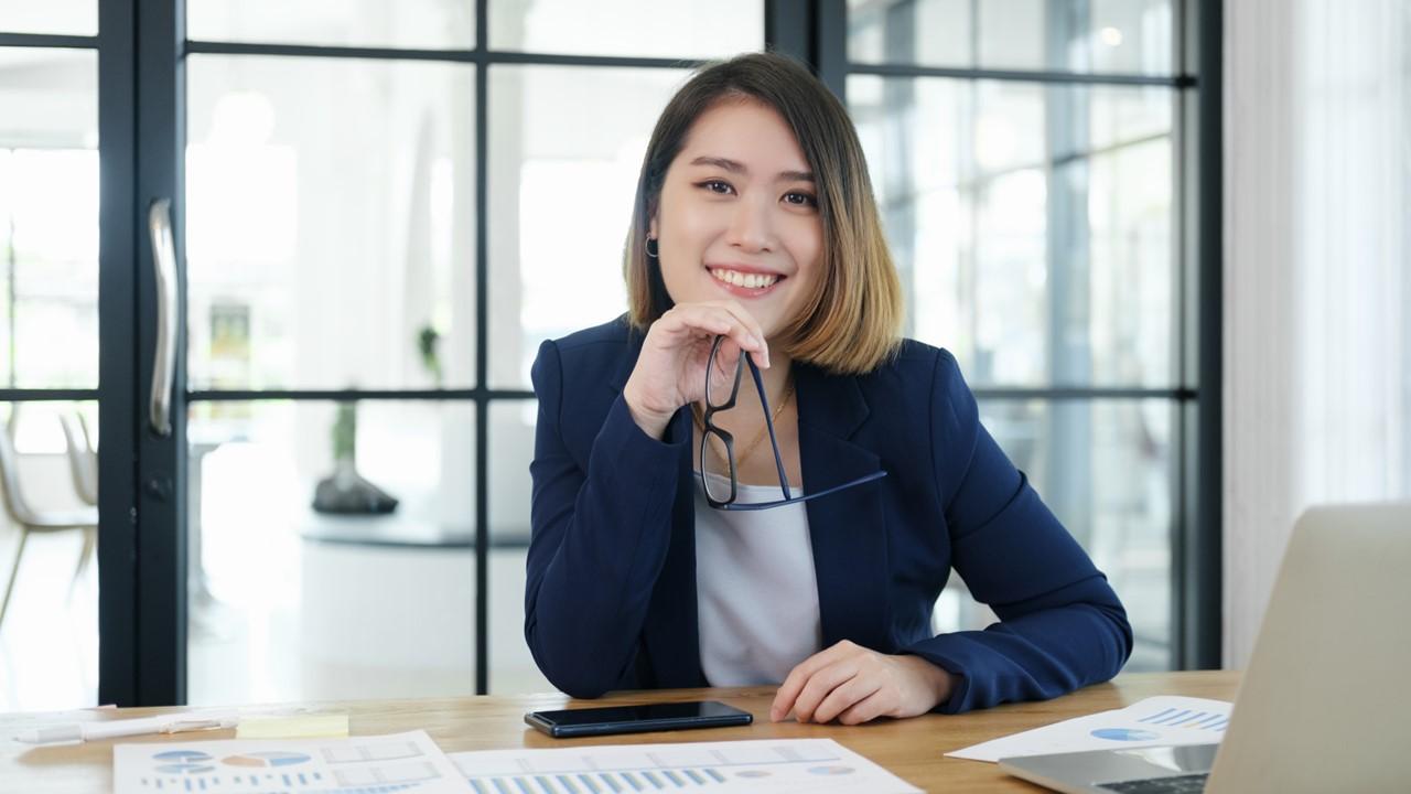 A female financial advisor wearing a navy blazer and sitting at a desk