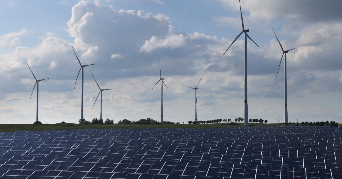 A field with solar panels and wind turbines