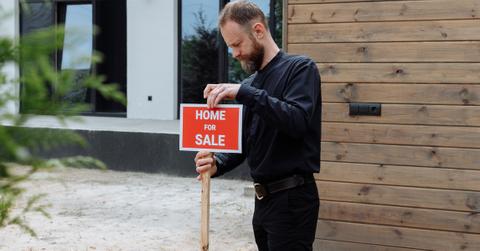 A person putting up a "home for sale" sign