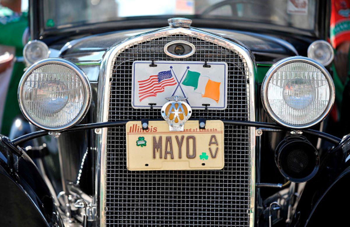 Antique car with an old license plate and Irish and American flag