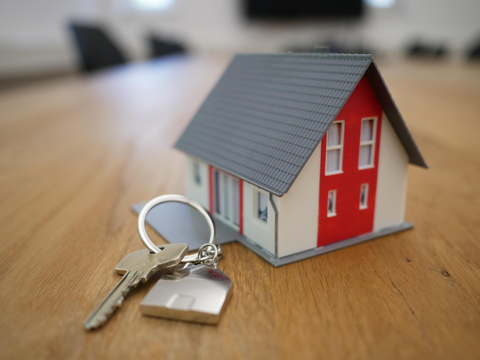 A red and white wooden toy house with metal keys lying to the side of it