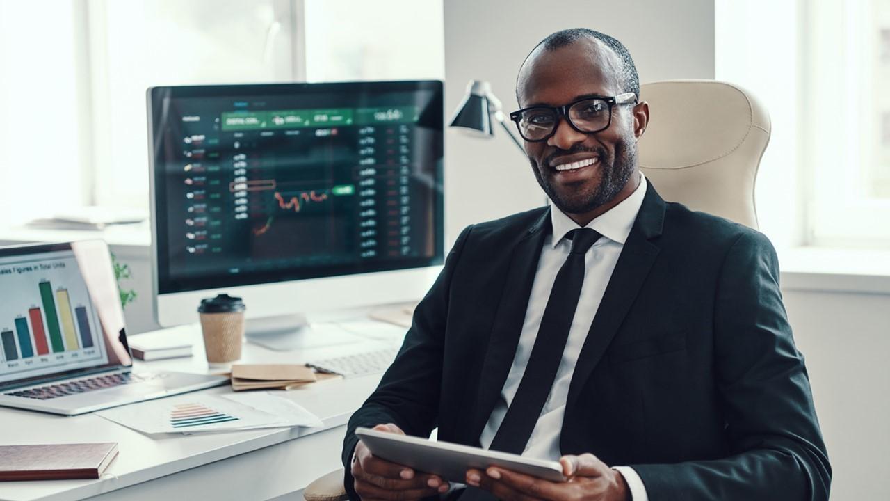 Man holding a tablet and sitting near computers