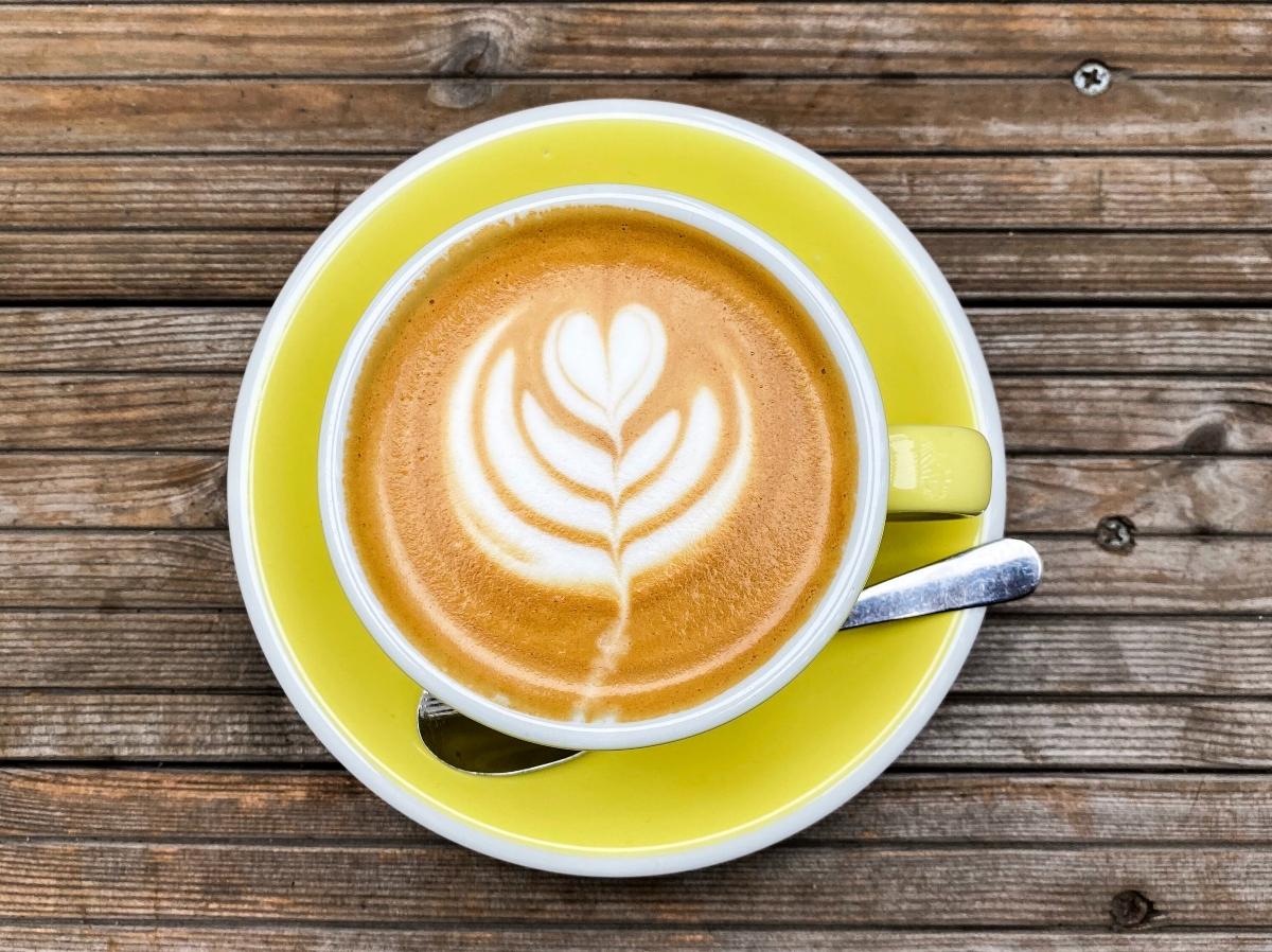 A latte in a yellow cup on a matching saucer