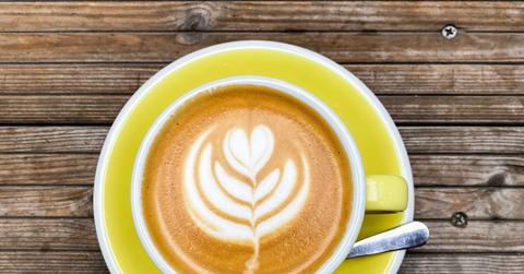 A latte in a yellow cup on a matching saucer