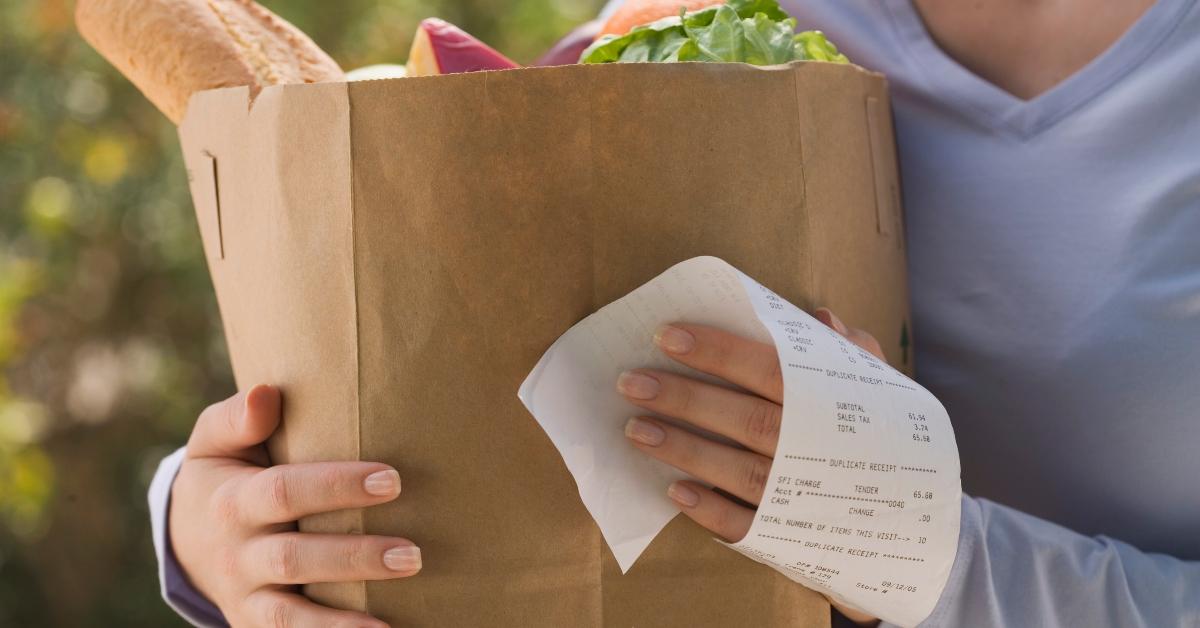 A person holding a receipt and grocery bag