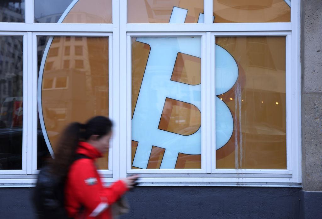 Woman walking in front of a Bitcoin sign