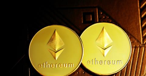 Two Ethereum coins placed on a wood carving