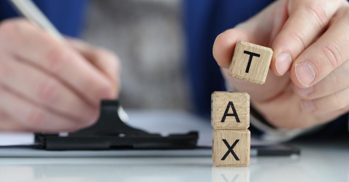 A person forms the word "tax" with building blocks while filling out tax forms.