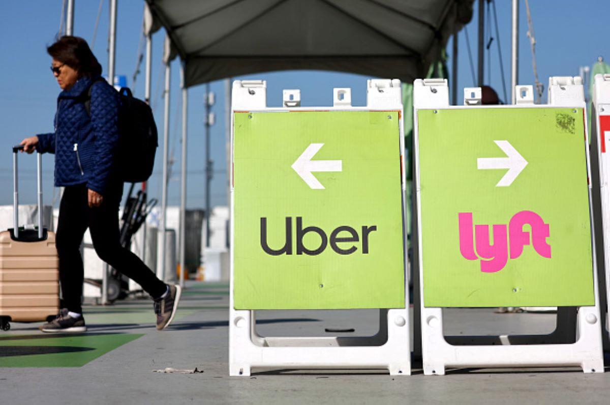 Woman walks past Uber and Lyft signs at the pickup area of LAX