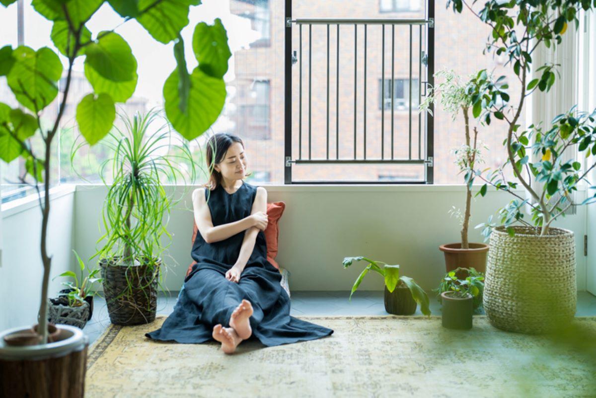 A woman relaxing in a room surrounded by potted plants