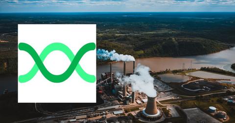 Smokestacks of a factory beside a river and forest