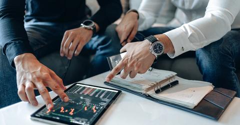 People pointing to a tablet displaying stock prices