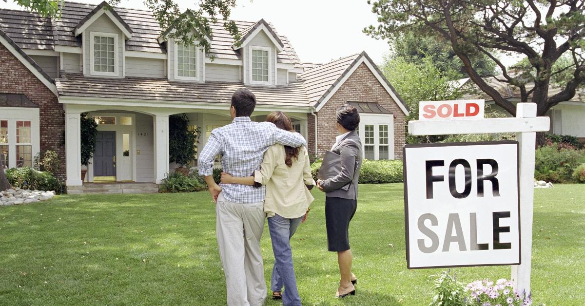 A couple in front of a house with a sold sign