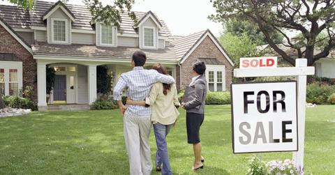 A couple in front of a house with a sold sign