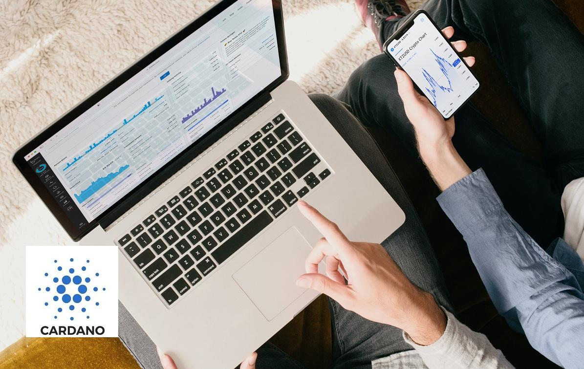 Two people looking at crypto charts on a laptop and smartphone