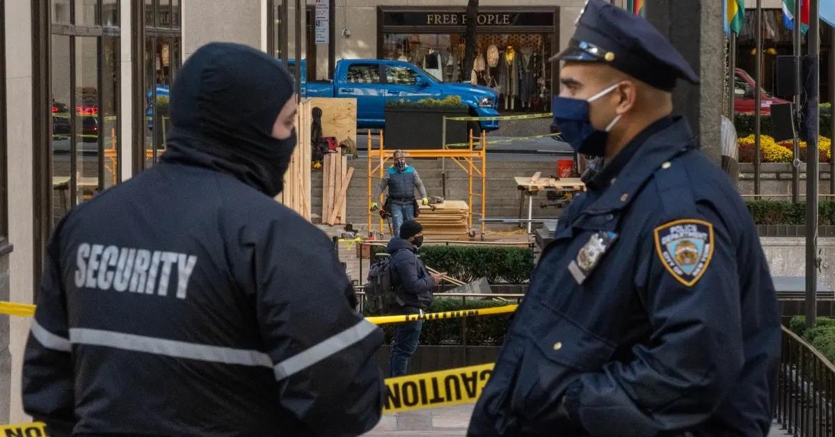 A police officer and security guard speaking in front of a retail store.