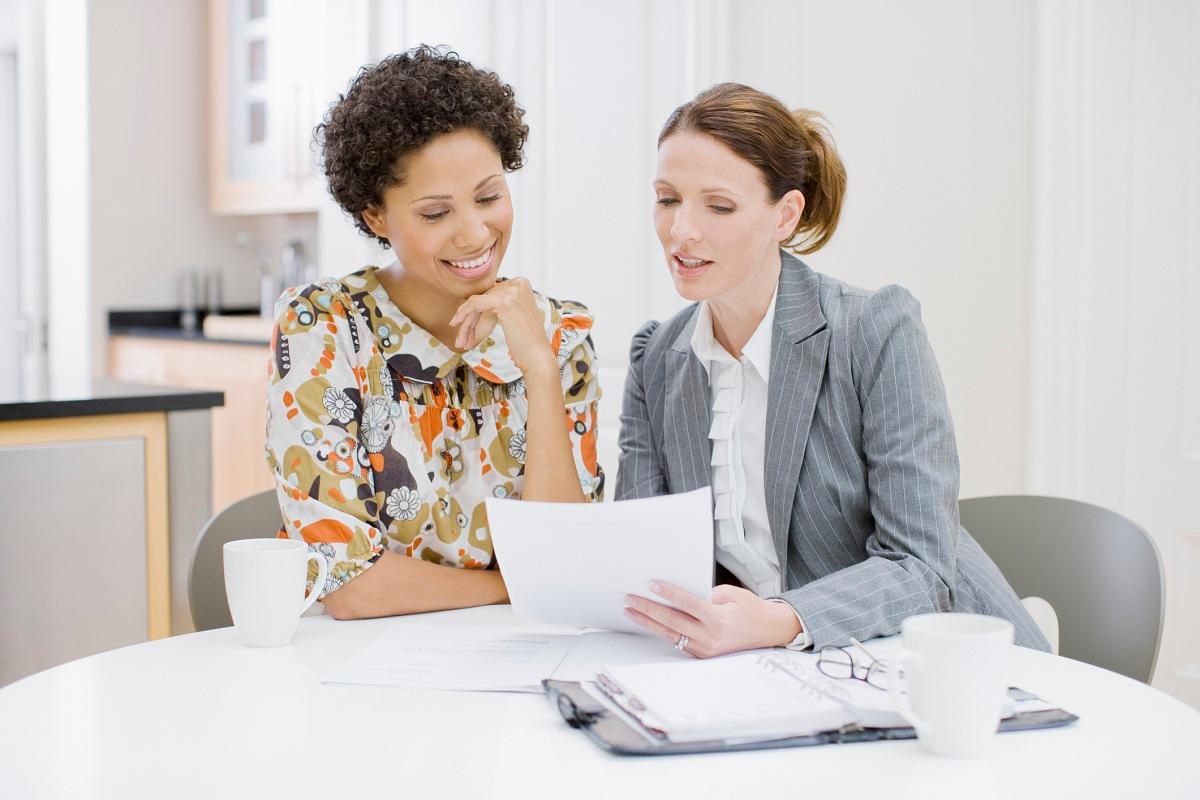 Businesswoman reviewing paperwork with woman