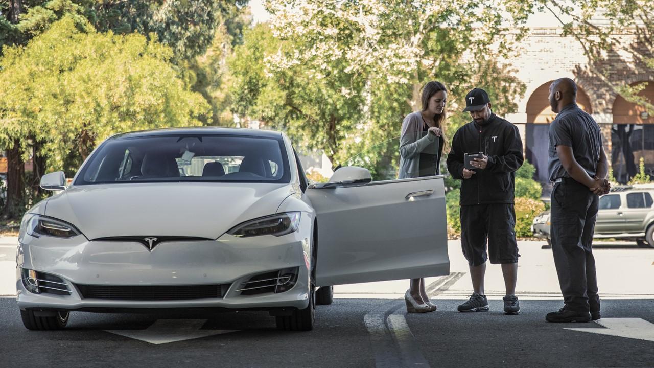 Tesla employees helping a customer