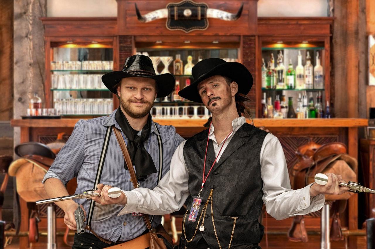 Two people dressed in Old West clothes holding guns